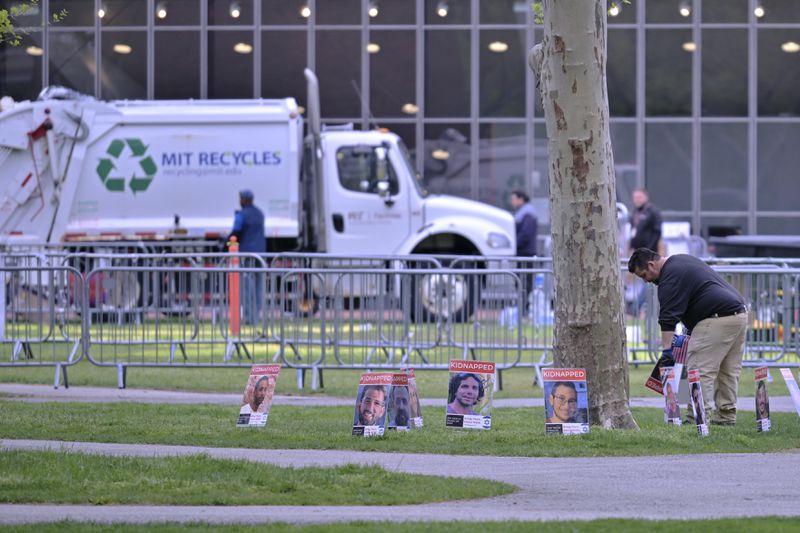 A man removes posters of Israeli hostages from a pro-Israeli display, which were the last items to be removed from the area after police raided and dismantled the pro-Palestinian encampment at MIT, which police raided before dawn Friday, May 10, 2024, in Cambridge, Mass. (AP Photo/Josh Reynolds)