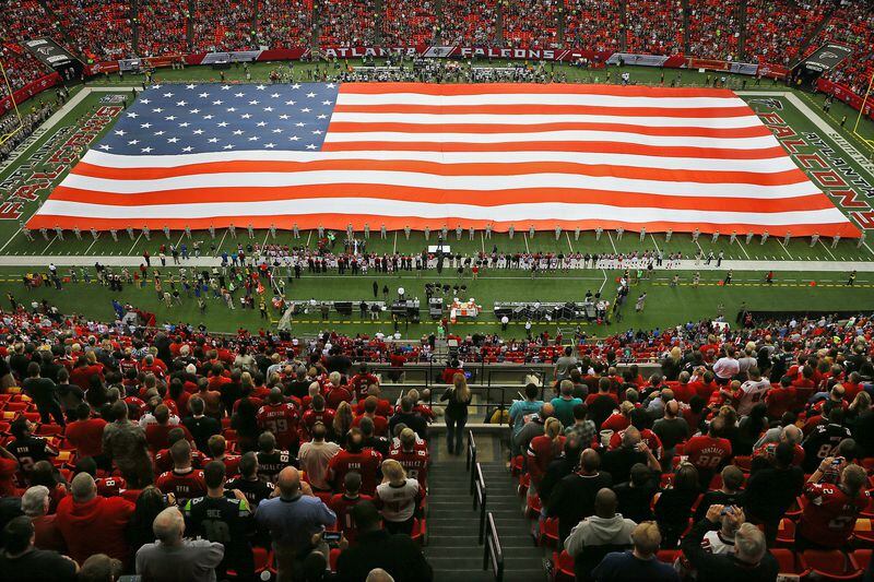 111013 ATLANTA: Falcons fans stand for the national anthem while around 100 soldiers from the Georgia Army National Guard unfold a giant American flag to commemorate Veteran's Day in a "Salute to Service" game vs the Seahawks on Sunday, Nov. 10, 2013, in Atlanta. CURTIS COMPTON /staff CCOMPTON@AJC.COM