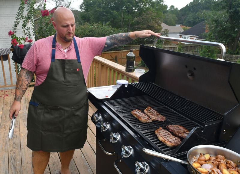 New York strip steaks get about three minutes on each side for how chef Pat Pascarella likes them done. The site of his grill overlooks his expansive backyard at his home in Roswell. He says the large backyard will soon be a vegetable garden. (Chris Hunt for the AJC)