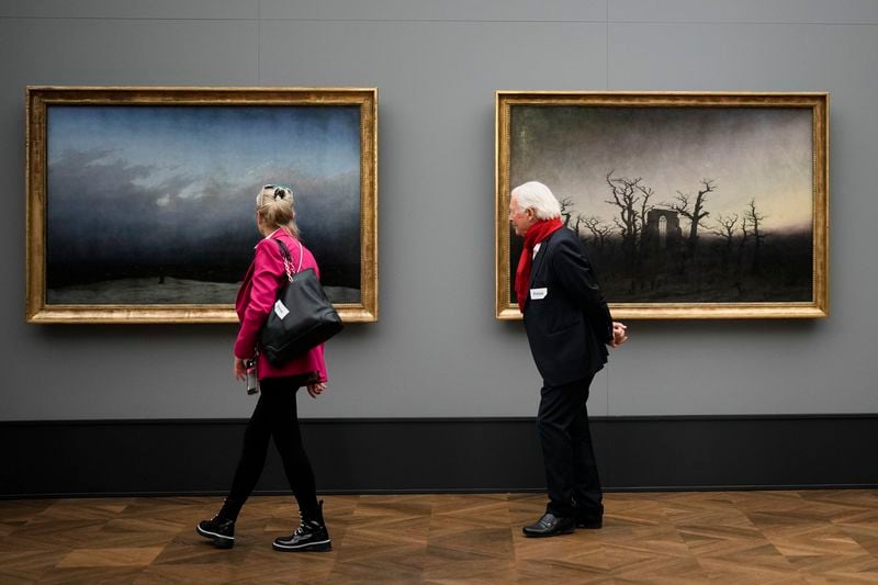 A couple walk in front of the painings 'Monk By The Sea', left, and ' Abby Among The Oaks' during a press preview of the exhibition 'Caspar David Friedrich. Infinite Landscapes' at the Alte Nationalgalerie museum in Berlin, Wednesday, April 17, 2024. The exhibition marking the 250th birthday of Caspar David Friedrich and will run from April 19 until August 4, 2024. (AP Photo/Markus Schreiber)