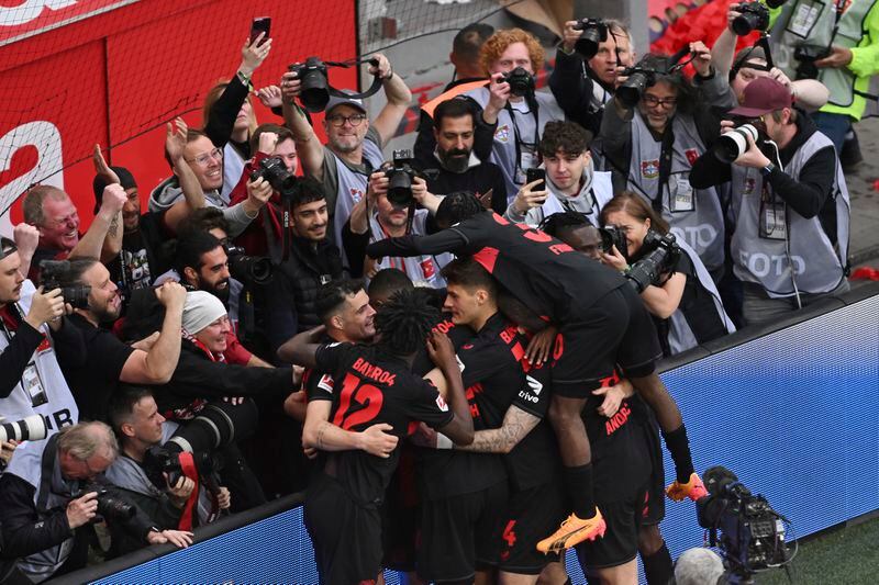 Leverkusen players celebrate after scoring their side's third goal of the game during the Bundesliga soccer match between Bayer Leverkusen and Werder Bremen at the BayArena in Leverkusen, Germany, Sunday April 14, 2024. (David Inderlied/dpa via AP)