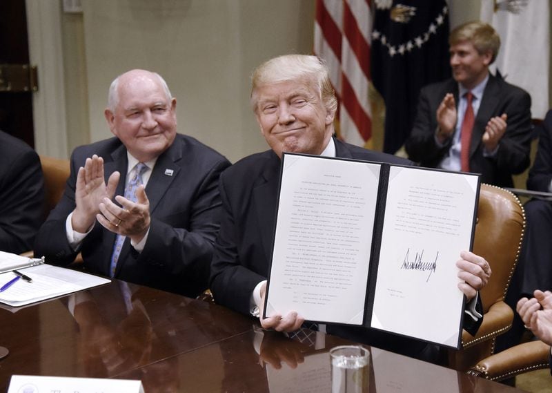 U.S. President Donald Trump signs the Executive Order Promoting Agriculture and Rural Prosperity in America as Agriculture Secretary Sonny Perdue looks on during a meeting with farmers on Tuesday, April 25, 2017, in the Roosevelt Room of the White House in Washington, D.C. (Olivier Douliery/Abaca Press/TNS)