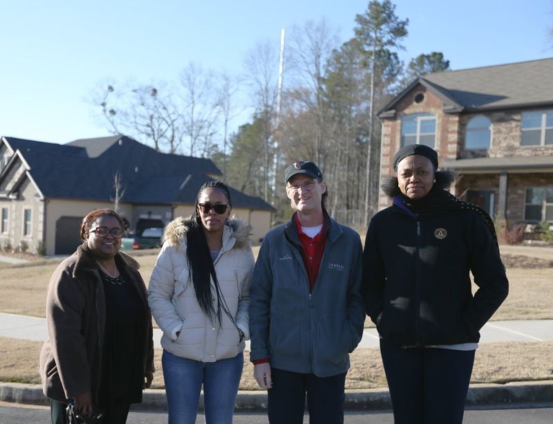 From left: Katrina Langford, Lynn Goodwin, Phillip Kelly and Virginia Pierce-Kelly stand in their Stonecrest neighborhood, in front of the cell tower that was built behind their homes. (Photo: EMILY HANEY / emily.haney@ajc.com)