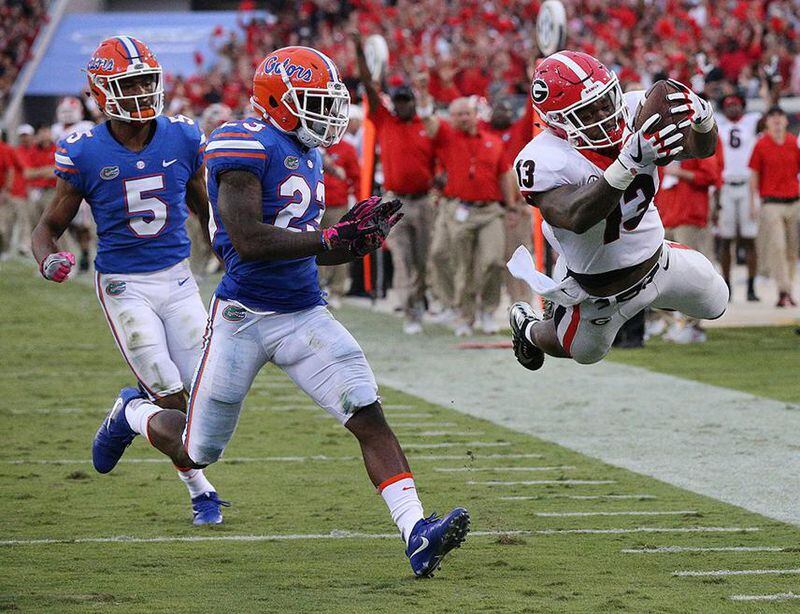 Georgia tailback Elijah Holyfield soars into the end zone past Florida defenders C.J. Henderson and Chauncey Gardner Jr. to take a 42-0 lead during the fourth quarter in the Georgia-Florida game in Jacksonville in 2017. Georgia beat Florida 42-7. Curtis Compton/ccompton@ajc.com