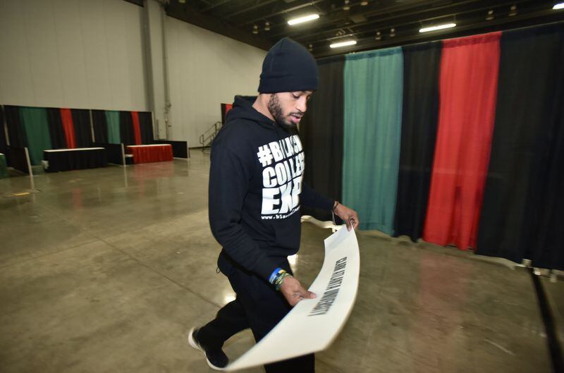 Derek Speight, event staff, carries a Clark Atlanta University banner during preparations for the Black College Expo at the Cobb Galleria Centre. HYOSUB SHIN / HSHIN@AJC.COM