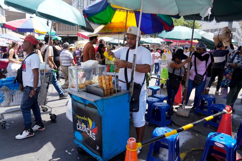 Venezuelan Giovanny Tovar waits for customers at his tequeños or fried breaded cheese sticks' street cart, in Lima, Peru, Saturday, April 13, 2024. Tovar is one of millions of Venezuelans living abroad who will not be able to cast his vote in the July 28th presidential election. (AP Photo/Martin Mejia)