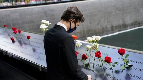 Mourners pause at the north reflecting pool as flowers are placed in the names of the dead at the National September 11 Memorial and Museum, Friday, Sept. 11, 2020, in New York. (John Minchillo / Associated Press)