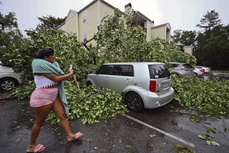 A resident records the damage to cars outside an apartment complex in Tallahassee, Fla., Friday, May 10, 2024. Powerful storms bringing the threat of tornadoes continued to slam several southern states early Friday, as residents cleared debris from deadly severe weather that produced twisters in Michigan, Tennessee and other states. Some of the strongest storms early Friday rolled into Tallahassee (AP Photo/Phil Sears)