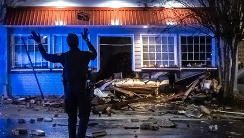 Atlanta police officers throw rocks and debris out of the road along Ponce de Leon Avenue after the roof of Mary Mac’s Tea Room partially collapsed overnight Wednesday.