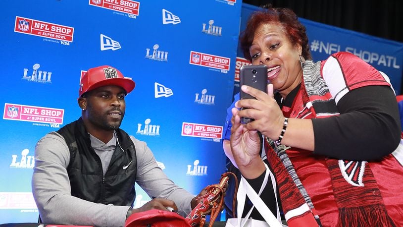 Jan. 31, 2019 Atlanta: Falcons fan Jan Radford snaps a selfie with former Falcons quarterback Michael Vick while he autographs items in the NFL Shop at the Super Bowl Experience on Thursday, Jan. 31, 2019, in Atlanta. Vick has a special edition New Era hat on sale in the NFL Shop.   Curtis Compton/ccompton@ajc.com