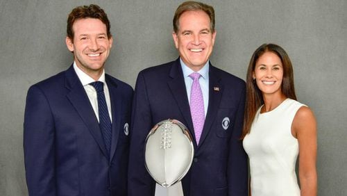 CBS' lead NFL broadcast team of (l-r) Tony Romo, Jim Nantz and Tracy Wolfson stand behind the Lombardi Trophy, presented each year to the Super Bowl winner.
