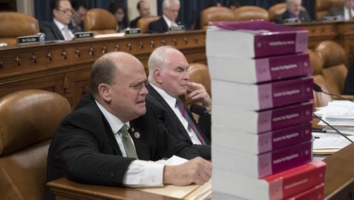 Seated behind a stack of IRS and tax volumes, Rep. Tom Reed, R-N.Y., left, joined by Rep. Mike Kelly, R-Pa., appeals to his Democratic opposition during debate on recent amendments to the House Republican tax reform plan, on Capitol Hill in Washington. (AP Photo/J. Scott Applewhite)
