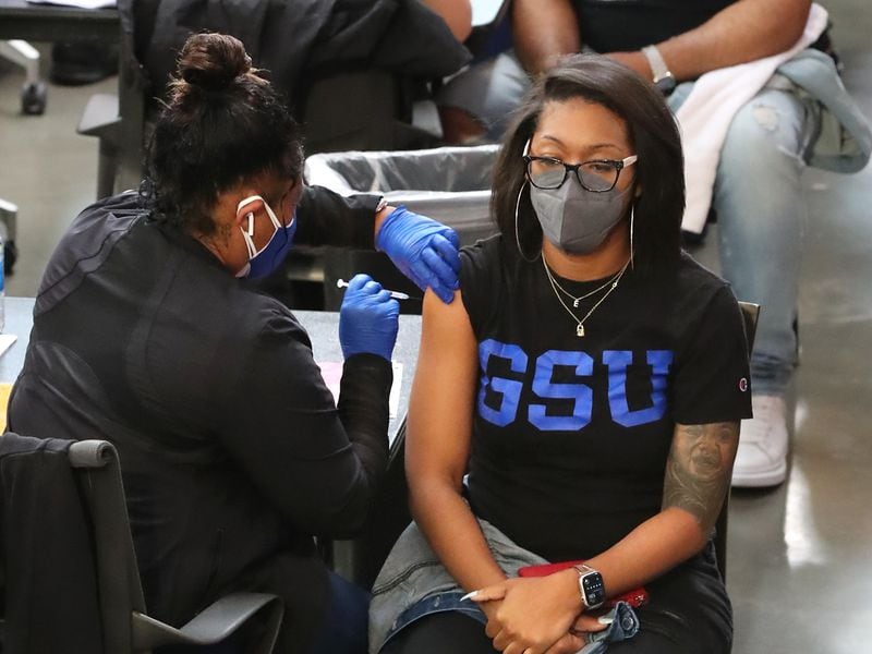 Teacher Eboni Moore (front right) is one of the first of approximately 1,200 Atlanta Public Schools employees to get a COVID-19 vaccine on Wednesday during a mass staff vaccination at Mercedes-Benz Stadium in Atlanta.  Curtis Compton / Curtis.Compton@ajc.com
