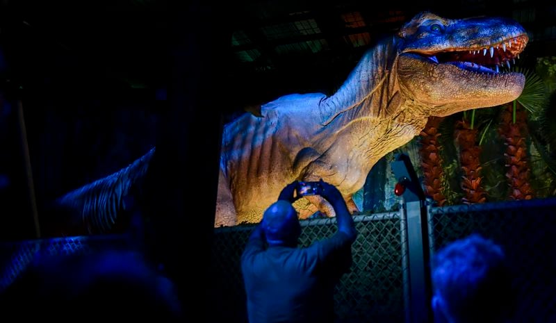 A visitor takes a photo as the T. rex roars at “Jurassic World: The Experience” in June at the Pullman Yards in Atlanta. Photo: Daniel Varnado/For the AJC