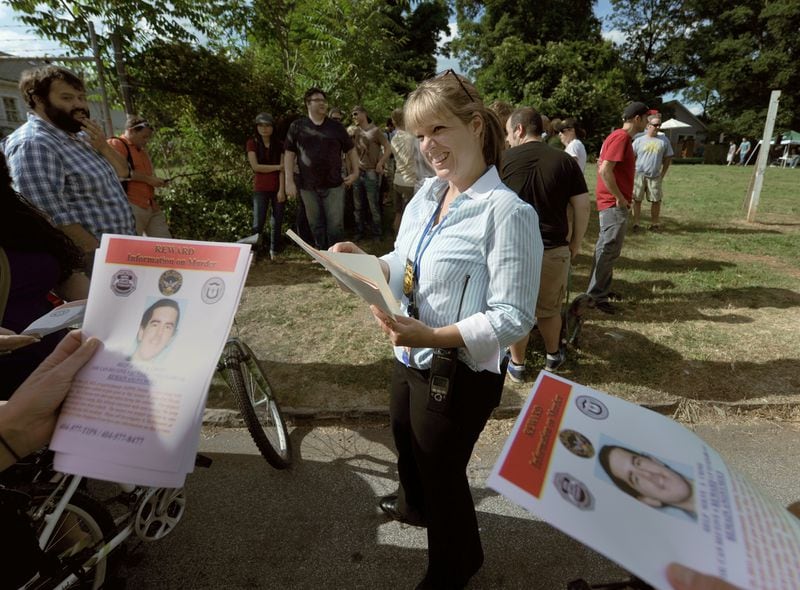Sgt. Paula Lyons, Atlanta Police Homicide Unit, passes out flyers offering $25,000 reward for information on the murder of Patrick Cotrona before the start of a a vigil and rally against crime in East Atlanta in this May 2013 file photo.