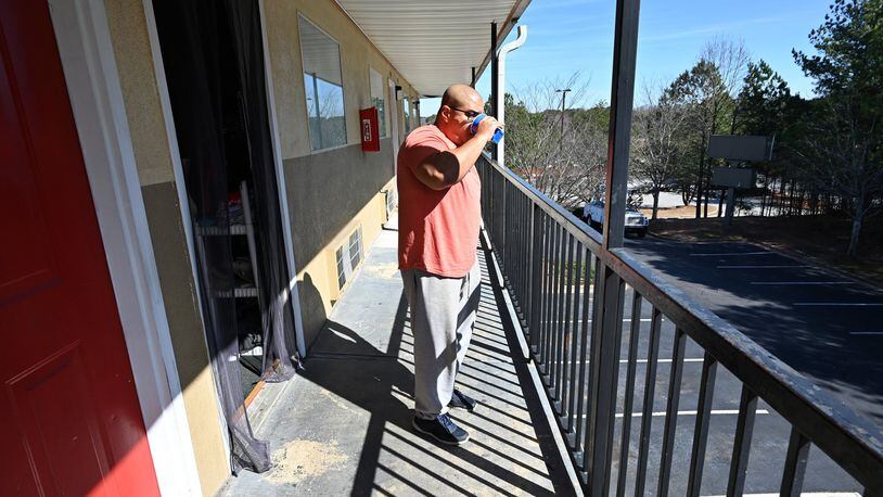 A resident of an extended-stay hotel gets some fresh air outside his room in Norcross. HYOSUB SHIN / HYOSUB.SHIN@AJC.COM
