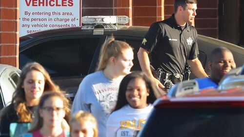 Students pass by a Laurens County Sheriff’s deputy stationed at East Laurens High School on Tuesday, May 2, 2018, in Dublin. Laurens County is the first school district in Georgia to allow teachers and other school personnel to carry weapons. An ad hoc school safety committee in Cherokee County, however, recently issued a report that opposes arming teachers and staff, other than certified police officers. Curtis Compton/ccompton@ajc.com (The Atlanta Journal-Constitution)