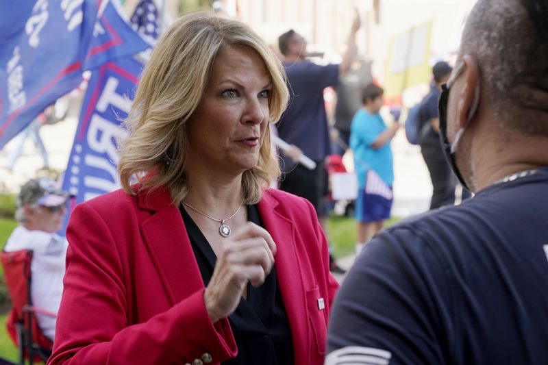 FILE - Dr. Kelli Ward, left, chair of the Arizona Republican Party, talks with a supporter of President Donald Trump as they join the crowd at a rally outside the Arizona Capitol, Nov. 7, 2020, in Phoenix. Ward is one of 11 Republicans in Arizona who submitted a document to Congress falsely declaring Donald Trump had beaten Joe Biden in the state during the 2020 presidential election were charged Wednesday, April 24, 2024 with conspiracy, fraud and forgery. (AP Photo/Ross D. Franklin, File)