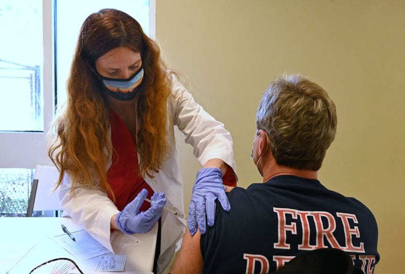 The first doses of the authorized vaccines were designated for health care workers and residents and staff of long-term care facilities. Captain David Weems (right), at Chattahoochee Hills Fire & Rescue, receives a Pfizer-BioNtech COVID-19 vaccine from Rebekah Revels, deputy chief nurse at the Georgia Department of Public Health, at Wolf Creek Amphitheater in late December. (Hyosub Shin / Hyosub.Shin@ajc.com)