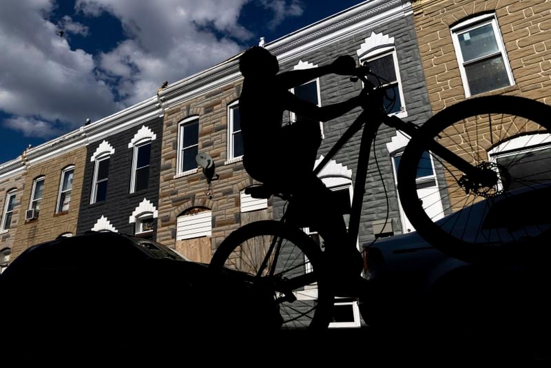 A boy rides his bike during a vigil for Antonio Lee, Friday, Aug. 18, 2023, in Baltimore. Lee, 19, was shot and killed while squeegeeing in Baltimore. (AP Photo/Julia Nikhinson)
