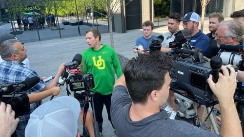 Oregon's first-year offensive coordinator Kenny Dillingham (green pullover) was the center of attention after Monday's practice as he fielded questions about the Ducks' ongoing quarterback battle. (Photo by Chip Towers/ctowers@ajc.com)