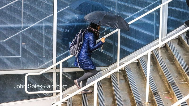 Ingrid Prieto makes her way upstairs from the Philips Arena MARTA station on a rainy Friday. JOHN SPINK / JSPINK@AJC.COM