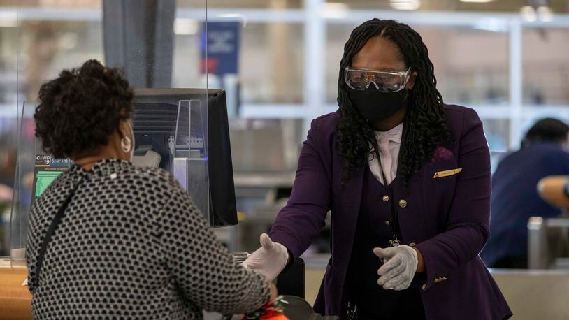 A Delta Air Lines employee handles a passenger's luggage while wearing goggle, gloves and a face mask in the domestic terminal at Hartsfield-Jackson Atlanta International Airport in Atlanta on Monday, Nov. 23, 2020.  (Alyssa Pointer / Alyssa.Pointer@ajc.com)