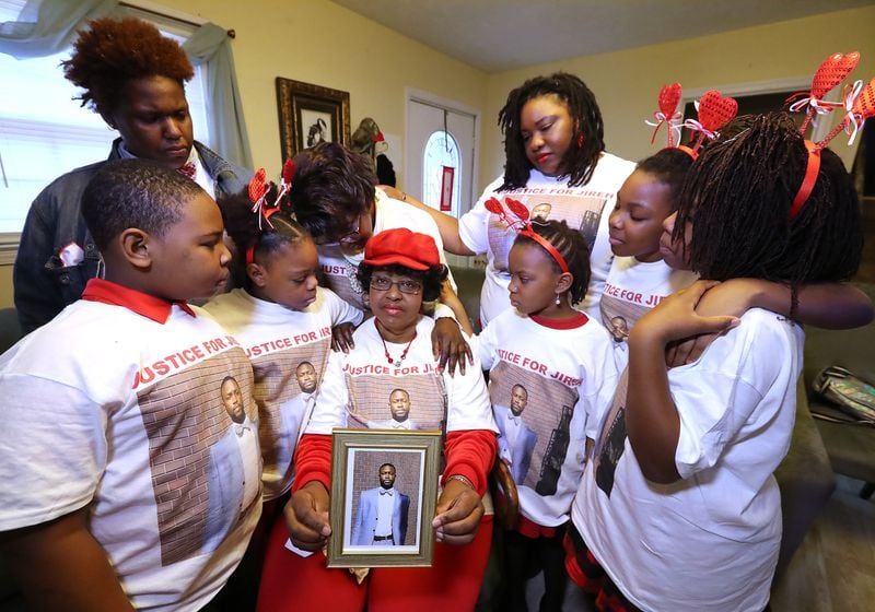 013121 Stone Mountain: Janet Morris (center) holds a picture of her son Jireh Morris, who was killed in a December shooting at a DeKalb County apartment complex, while being consoled by family members wearing justice shirts bearing Jireh’s picture at the family home on Sunday, Jan. 31, 2021, in Stone Mountain. From left are  grandchildren Nolan Demond Evans, daughter Brittany Michelle Morris, Jana Marie Evans, mother Jeanette Ingersoll, daughter Lana Marie Starks, Zoey Marie Starks, Laia Cristina-Janet Starks, and Skylar Michell Starks.    Curtis Compton / Curtis.Compton@ajc.com”