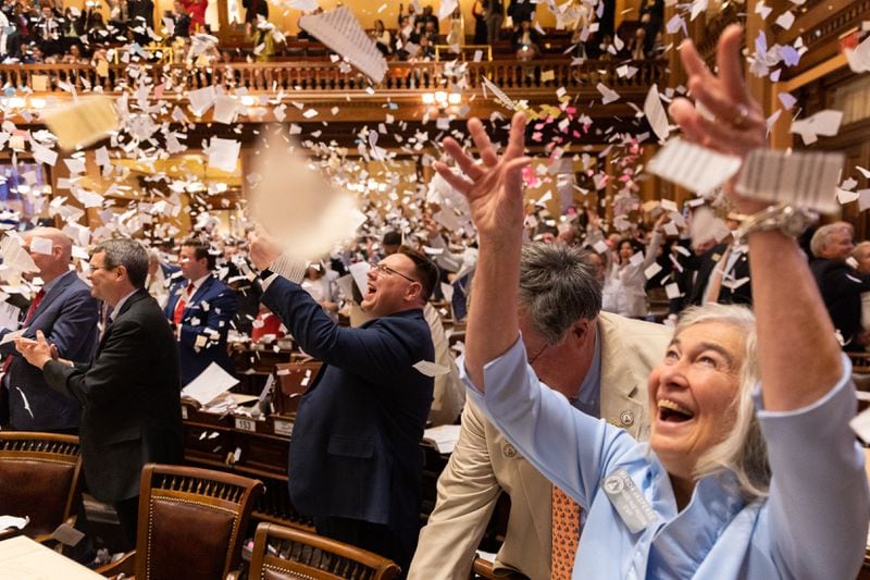 State representatives throw paper in the air to celebrate the end of the legislative session.