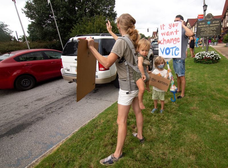  An Avondale Alliance for Racial Justice demonstrator Katie Jane Labauve and her daughter Elois holds up a sign as cars drive by in Avondale Estates's downtown strip Saturday, August 29, 2020.  STEVE SCHAEFER FOR THE ATLANTA JOURNAL-CONSTITUTION