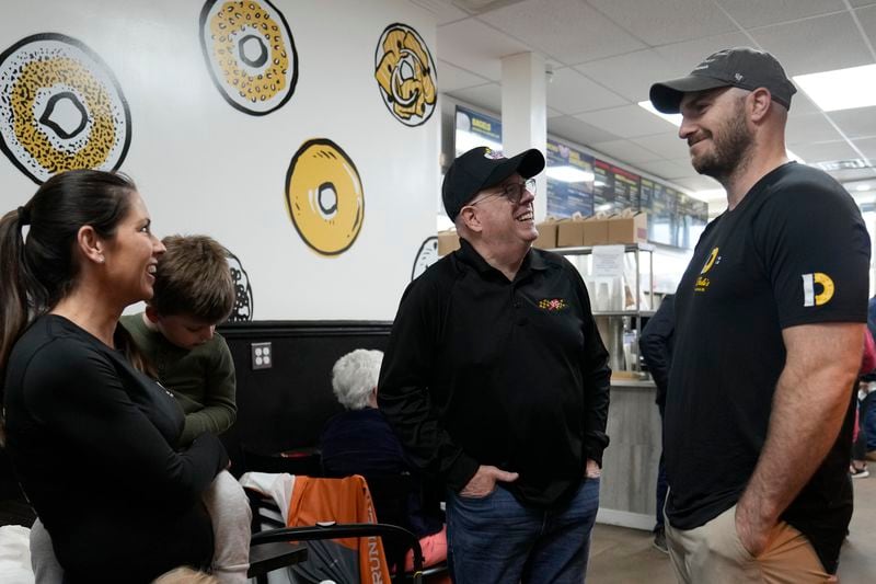 Former Maryland Gov. Larry Hogan, center, talks with Andrew DePaola, right, and his wife Amy DePaola, both of DePaola's Bagel and Brunch in Stevensville, Md., Friday, April 12, 2024, as Hogan campaigns for the U.S. Senate. (AP Photo/Susan Walsh)