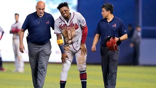 Atlanta Braves right fielder Ronald Acuna Jr., center, attempts to walk after trying to make a catch on an inside-the-park home run hit by Miami Marlins' Jazz Chisholm Jr. during the fifth inning of a baseball game, Saturday, July 10, 2021, in Miami.