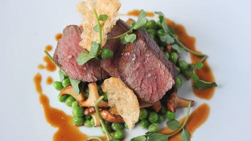 Dry-aged rib-eye is served with English peas, chanterelle mushrooms, puffed beef tendon and wild watercress at Five and Ten in Athens. (Becky Stein)