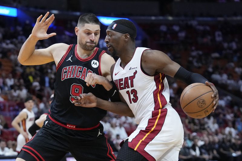 Miami Heat center Bam Adebayo (13) drives to the basket against Chicago Bulls center Nikola Vucevic (9) during the first half of an NBA basketball play-in tournament game, Friday, April 19, 2024, in Miami. (AP Photo/Wilfredo Lee)