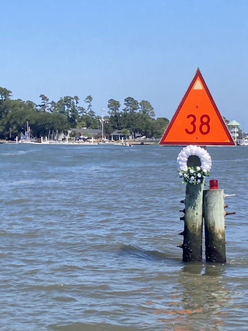 A wreath hangs on a channel marker in the Wilmington River near the Savannah Yacht Club. A boat struck the channel marker in May 2022, killing a passenger, one of three serious boating incidents that happened within a month in Savannah. (Adam Van Brimmer/AJC)