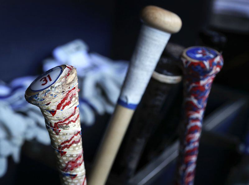 In this Friday, Aug. 4, 2017 photo, Los Angeles Dodgers' Joc Pederson's bat, left, rests in the dugout before a baseball game against the New York Mets in New York. Pederson is among the most recent major leaguers to adopt the Axe Bat handle, a modern take on the baseball bat that eschews the traditional round knob. (AP Photo/Julie Jacobson)