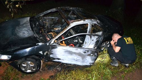 A fire investigator examines a car involved in a fiery crash late Wednesday. (Tim Cavender/Cherokee County fire department)
