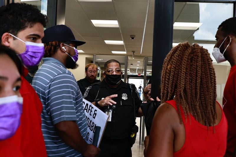 A police officer speaks to activists and residents of the Forest at Columbia Apartments Thursday as the protest group attempted to enter the Manuel J. Maloof Center to speak with county commissioners.