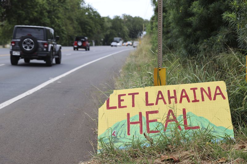 A sign stating "Let Lahaina Heal" is seen on the side of the highway, Friday, April 12, 2024, in Kanapali, Hawaii. More than half a year after the deadliest U.S. wildfire in more than a century burned through a historic Maui town, officials are still trying to determine exactly what went wrong and how to prevent similar catastrophes in the future. But two reports released this week are filling in some of the blanks. (AP Photo/Marco Garcia)