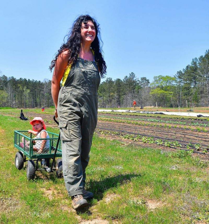 Levity Farms owner Ilana Richards pulls daughter Harlyn along in a plant cart during a tour of the Madison farm. (Chris Hunt for The Atlanta Journal-Constitution)
