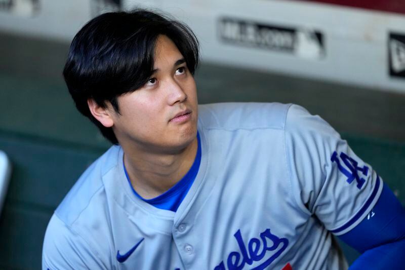 Los Angeles Dodgers Shohei Ohtani looks toward a swarm of bees gathering on the net behind home plate delaying the start of a baseball game against the Arizona Diamondbacks, Tuesday, April 30, 2024, in Phoenix. (AP Photo/Matt York)
