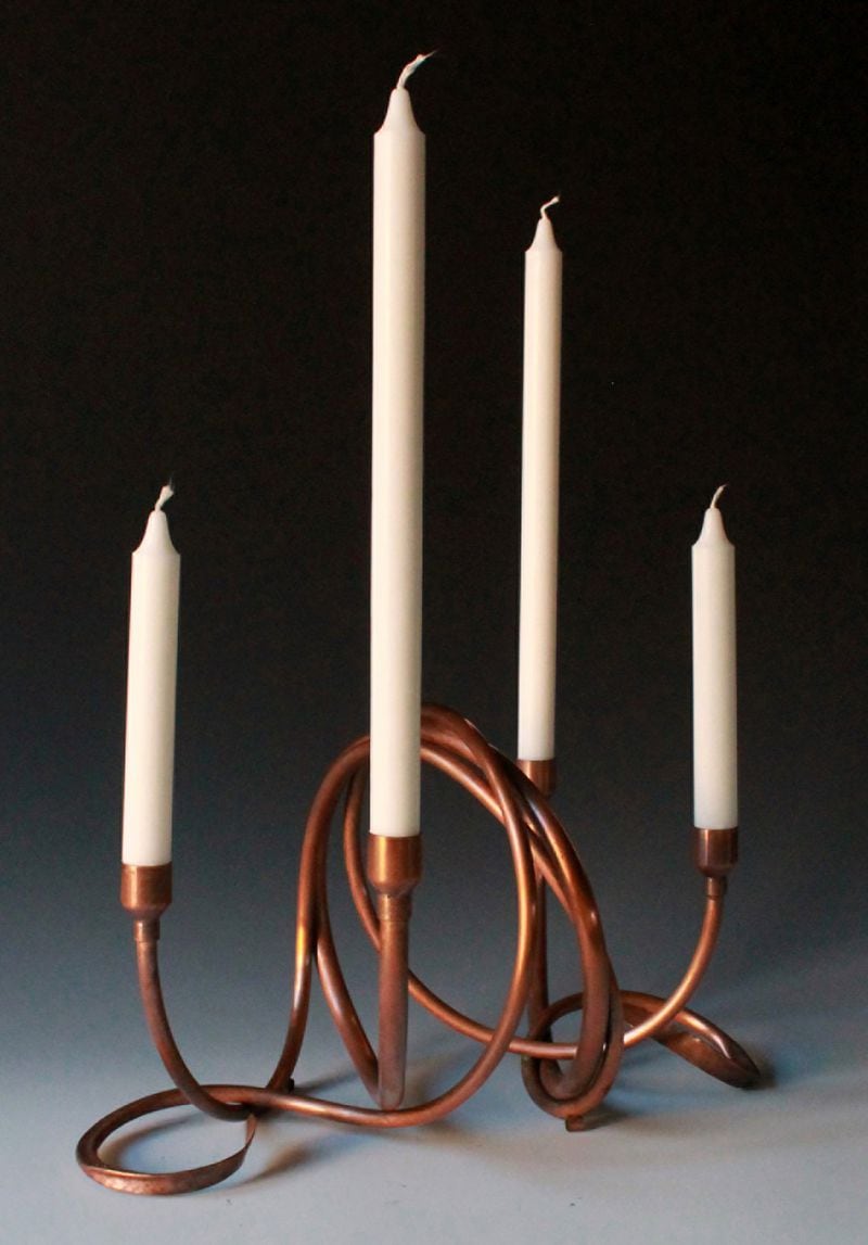 Many of Cathy Vaughn’s copper pieces, like her various modern candle holders, have hand-wrought curves and hammered details. While she bends copper tubing by hand, she also uses a hammer and anvil to flatten bent pipe or sheet. 