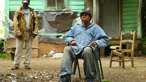 Adel Edwards, 54, sits outside his Pelham home by a small pile of leaves with his friend Henry Smith. Edwards was fined $500 for burning leaves without a permit and placed on probation to make payments. In a lawsuit, Edwards alleges he was jailed when he couldn’t afford to make a day-of-court payment demanded by the court’s probation company. Curtis Compton / ccompton@ajc.com