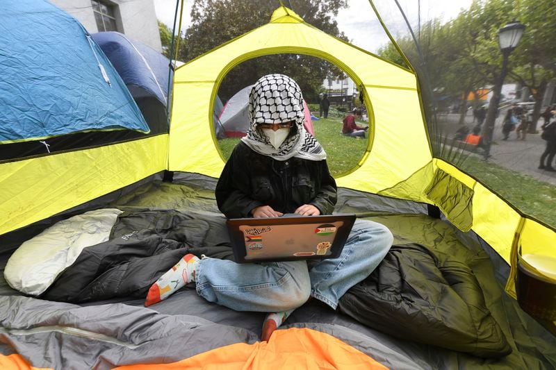 Isa, did not want to give last name, works on her laptop while sitting inside her tent while camped outside Sproul Hall during a protest on the campus of University of California, Berkeley in Berkeley, Calif., Thursday, April 25, 2024. Hundreds of pro-Palestinian protesters staged a demonstration in front of Sproul Hall where they set up a tent encampment and are demanding a permanent cease-fire in the war between Israel and Gaza. (Jose Carlos Fajardo/Bay Area News Group via AP)
