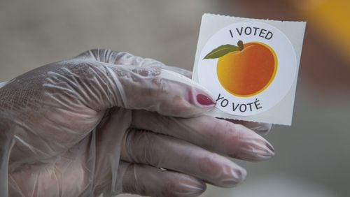 An early voter, who wore gloves to cast their ballot, shows off their sticker at the Gwinnett County Voter Registration and Elections Office in Lawrenceville, Monday, May 18, 2020. Gwinnett plans to translate more voting materials into additional languages. (ALYSSA POINTER / ALYSSA.POINTER@AJC.COM) AJC FILE PHOTO