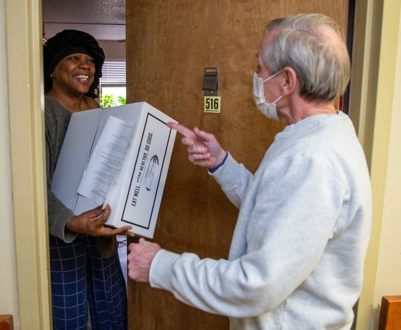 Frederica Broadney (left) greets volunteer driver Rob Muething as he hands her a box of meals from Open Hand Atlanta. PHIL SKINNER FOR THE ATLANTA JOURNAL-CONSTITUTION.