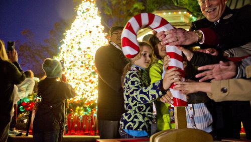 Cecily Sullivan (center) pushes the candy cane to turn on the lights on the main Christmas tree inside Six Flags Over Georgia in Austell on Friday, Nov. 21, 2014. Holiday in the Park runs through Jan.4, 2015. JONATHAN PHILLIPS / SPECIAL