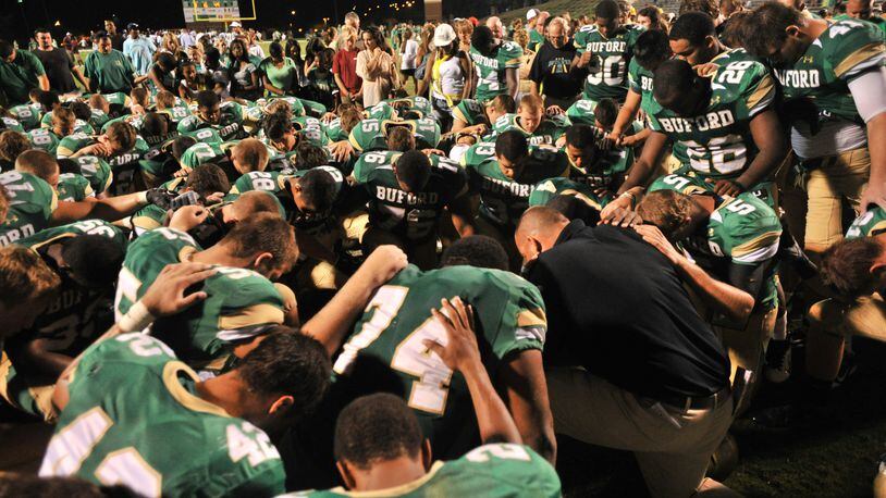 Buford head coach Jess Simpson (right corner) leads a prayer after their big win on Friday, September 2, 2011. (AJC file/Hyosub Shin)