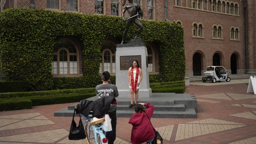A graduating senior takes photos under the University of Southern California mascot on campus, Thursday, April 25, 2024, in Los Angeles. (AP Photo/Jae C. Hong)