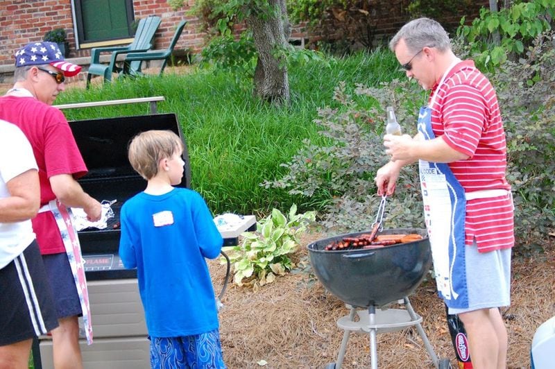 Todd Wilkes (right) grills hot dogs for one of the Faraday Place Fourth of July celebrations, with Trey Weathers (left) manning the second grill. CONTRIBUTED BY CHRIS BRINSON